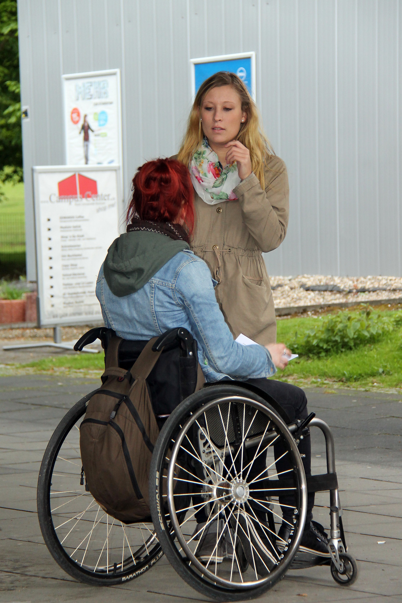 Participate image presenting two women talking to each other, one of which is sitting on a wheelchair.