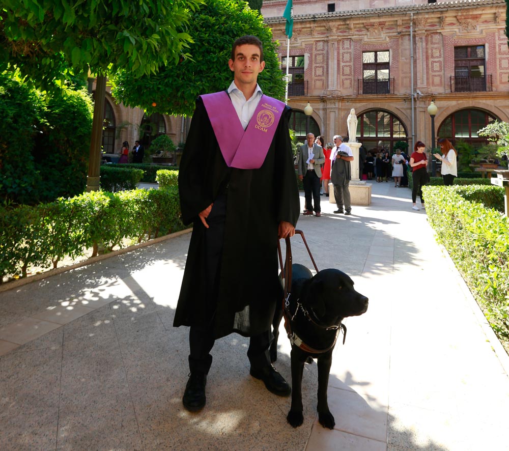 About us image presenting a student who has graduated with a labrador guide next to him.